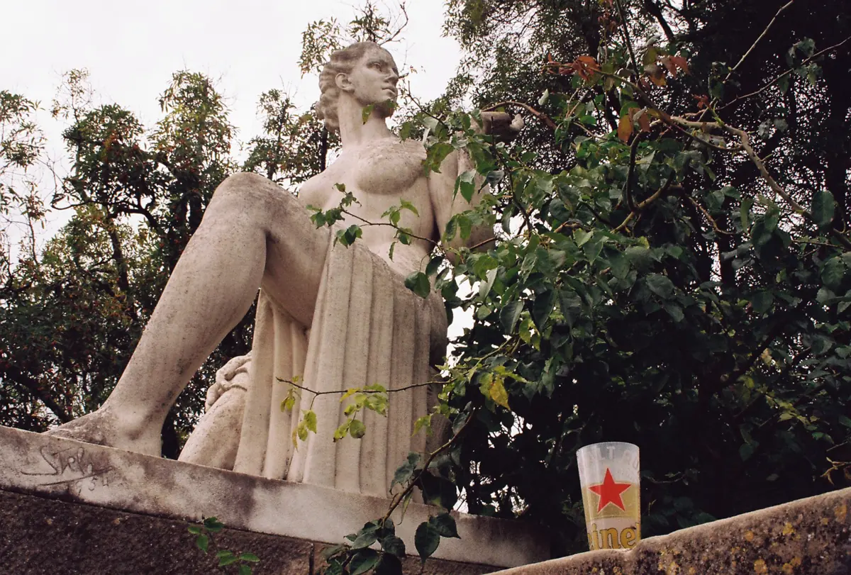 A marble statue of a seated woman among trees
