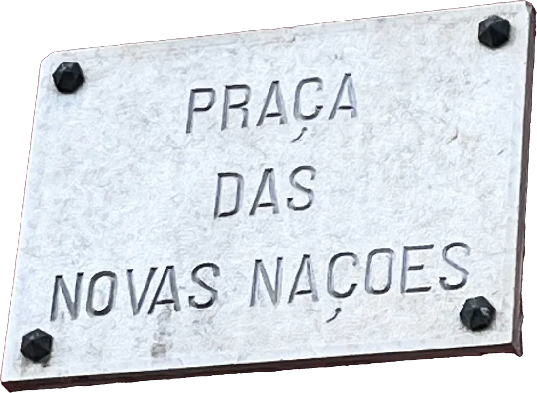 A weathered stone street sign plaque reading Praça das Novas Nações, mounted with four bolts