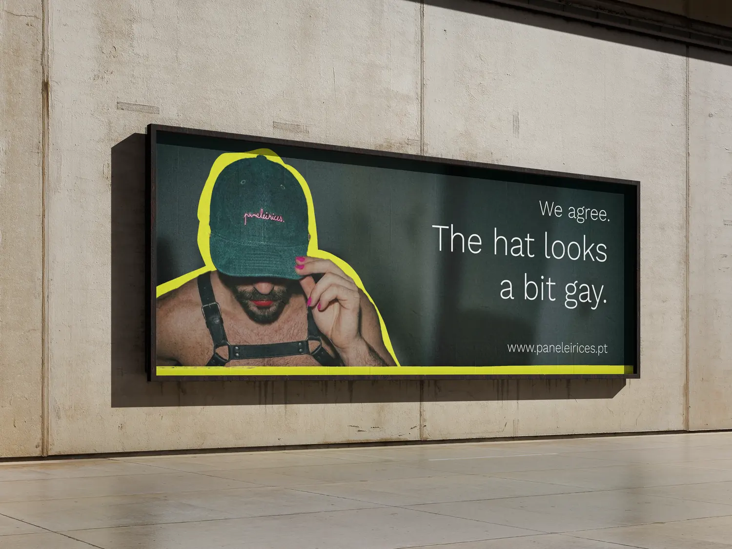 Billboard on a concrete wall: a man in a harness pulls a green cap over his face. “We agree. The hat looks a bit gay.”