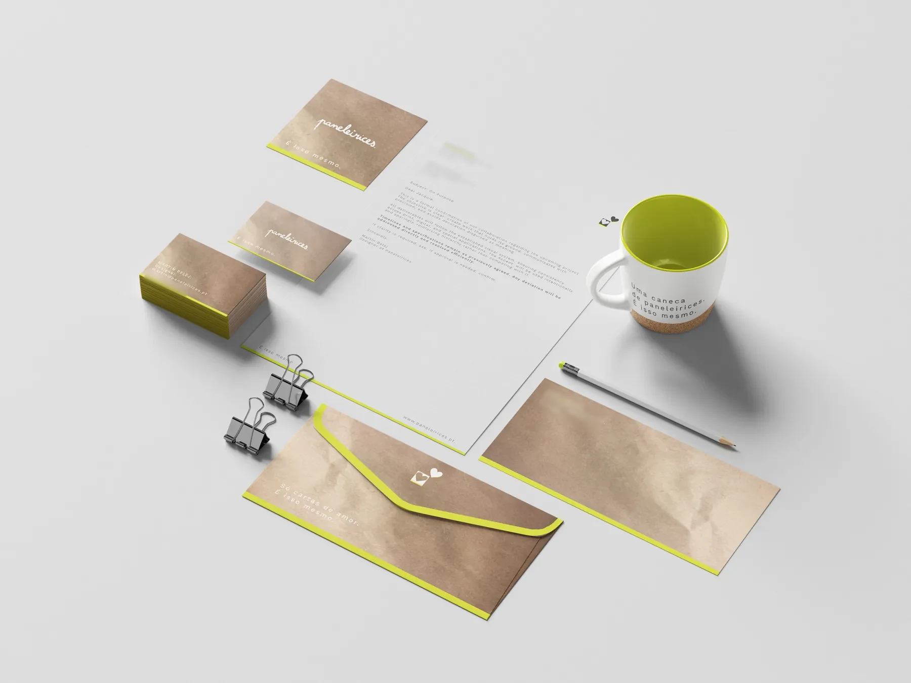Stationery set on a gray surface: kraft envelopes with a neon edge, business cards, letterhead and a mug