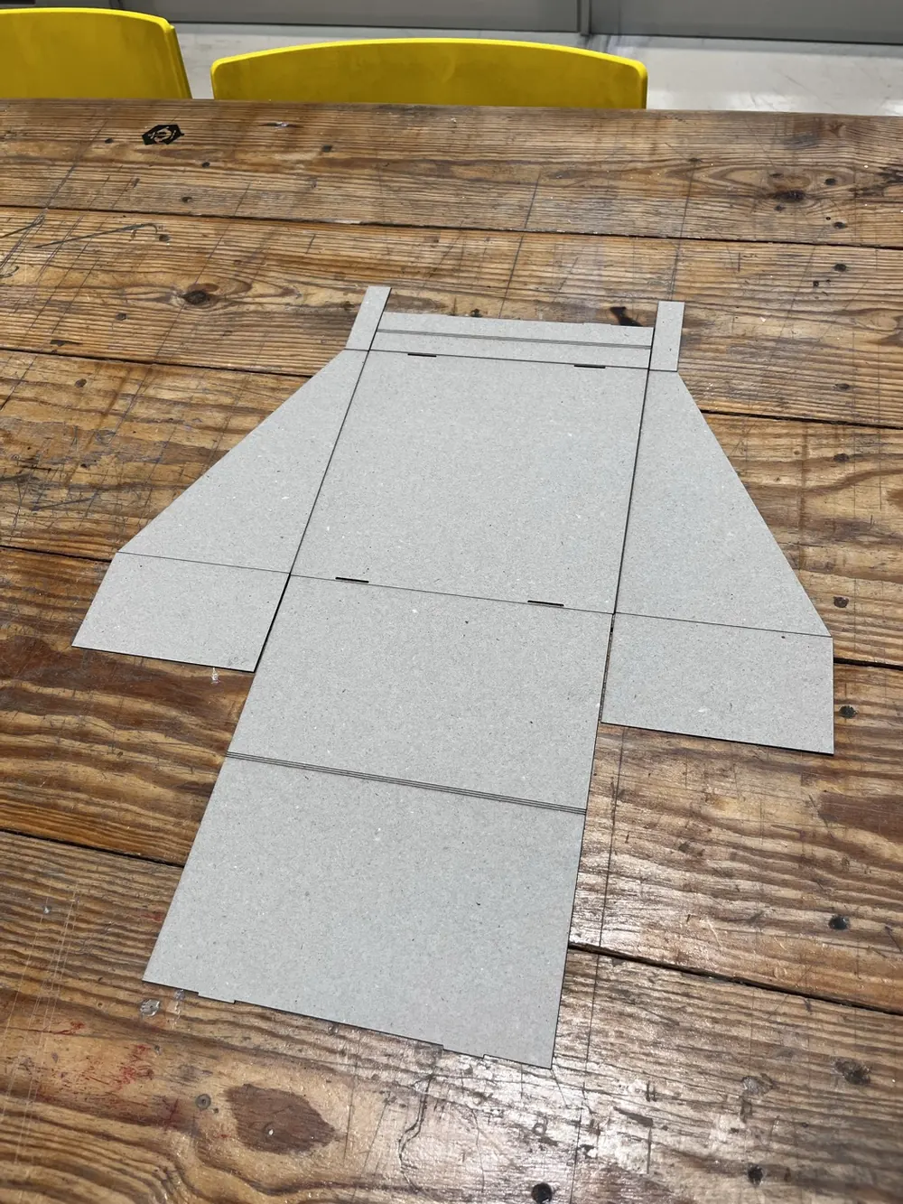 The flat piece cut from gray board, lying on a workshop table