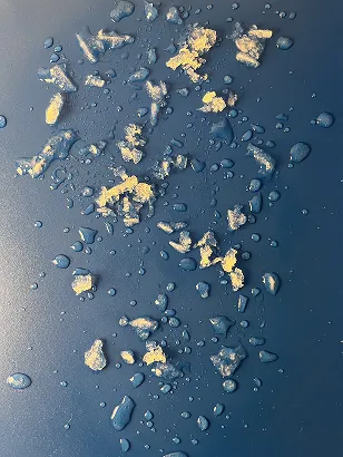 Frost crumbs and droplets on a dark blue surface